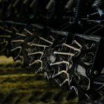 Um homem vestindo uma camisa de colarinho e óculos de aro preto sorri para a câmera.