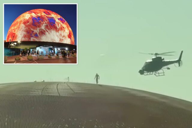 Um alpinista profissional nas paredes curvas do The Sphere, com um helicóptero filmando nas proximidades.