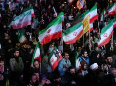 Fugi do Irão quando era bebé – agora o regime usa crianças como escudos humanos Uma grande multidão de pessoas segurando bandeiras iranianas à noite.