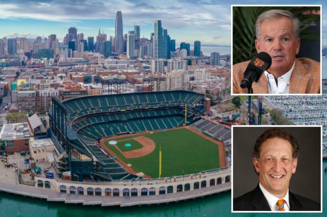 Um homem com cabelo curto e escuro e camisa de colarinho verde escuro gesticula com as mãos enquanto está sentado em uma cadeira branca.