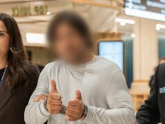 Golpista acusado de suposta armação em shopping center de US$ 150.000 em NSW O homem fez sinal de positivo para uma câmera no aeroporto de Sydney.