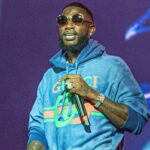 Gucci Mane se apresentando com um moletom Gucci azul e óculos escuros.