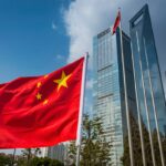 The vibrant red field and yellow stars of the Flag of the People's Republic of China flying in the breeze beside the futuristic glass and steel towers of Pudong's soaring skyscrapers, Shanghai, China.