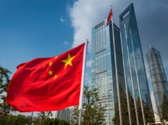 Hacker que supostamente realizou ataques cibernéticos para a China é extraditado para os EUA The vibrant red field and yellow stars of the Flag of the People's Republic of China flying in the breeze beside the futuristic glass and steel towers of Pudong's soaring skyscrapers, Shanghai, China.