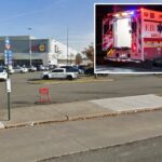 Uma placa de ponto de ônibus é visível na calçada ao lado de um grande estacionamento em frente a uma loja Primark e Lidl.