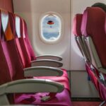 Fileira vazia de assentos de avião vermelhos.