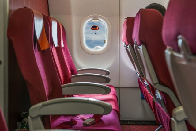 Fileira vazia de assentos de avião vermelhos.