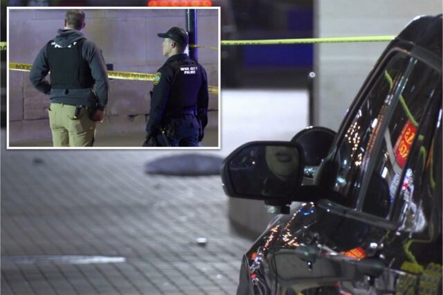 Dois policiais de Iowa City atrás da fita da cena do crime.