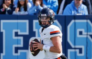 Juiz nega oferta de Virginia QB Chandler Morris para o sétimo ano de elegibilidade para a faculdade Chandler Morris vestindo uma camisa de futebol branca da Virgínia e capacete preto, segurando uma bola de futebol.