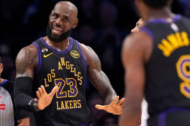 LeBron James com uniforme do Lakers com as mãos para cima, de frente para Bronny James, que está de costas para a câmera.
