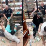 Dois detetives à paisana tentam prender um suspeito, com um detetive segurando a perna do suspeito, fazendo com que o suspeito caia no meio de garrafas quebradas em uma loja de bebidas.