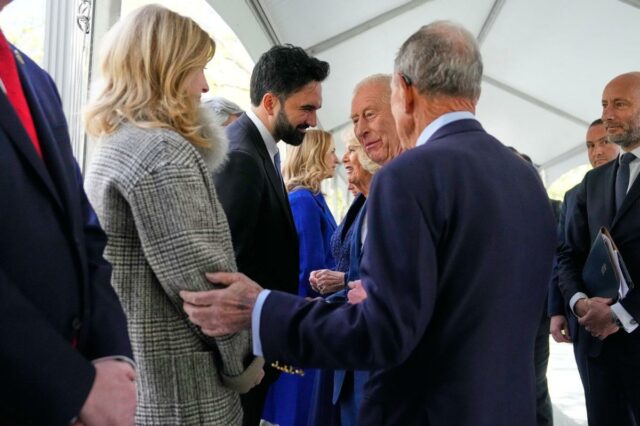Rei Carlos III e Rainha Camilla interagindo com convidados em evento.