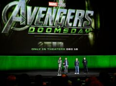 Marvel Studios retornará ao Hall H da Comic-Con neste verão | Exclusivo Robert Downey Jr. está no palco da Comic-Con fantasiado de Victor Doom e segura sua máscara voltada para o céu em um gesto triunfante