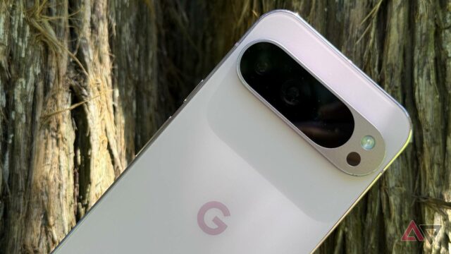 Uma mão segurando um smartphone Google Pixel azul com um ícone de alerta e ícones representando câmera, áudio e bugs.