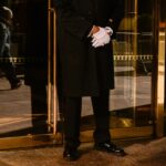 Um porteiro de casaco preto e luvas brancas está do lado de fora da Trump Tower.