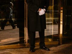 Milhares de porteiros e supers de Nova York ‘paralisam’ o estilo de vida chique da cidade com voto de greve Um porteiro de casaco preto e luvas brancas está do lado de fora da Trump Tower.