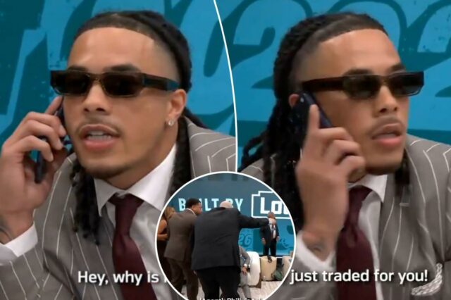 Um homem de terno listrado e óculos escuros fala ao telefone, dizendo 