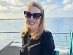 Mulher luta contra três tipos de câncer depois que o marido a traiu – e ela descobriu que tem uma DST que causa câncer Eileen McGill Fox sorri para a câmera, usando óculos escuros e blusa preta, com um corpo d'água e o horizonte ao fundo.