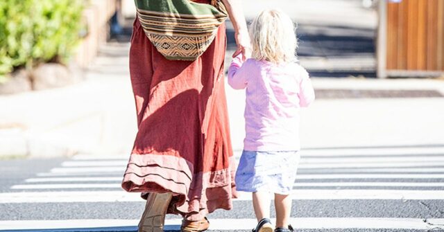 Imagem genérica de mãe e filho atravessando a rua.