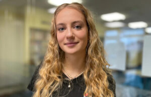 ‘Nossas bebidas foram fortalecidas quando tínhamos 15 anos’ Daisy tem cabelos castanhos longos e lisos e olhos escuros. Ela está vestindo uma camiseta preta e tem dois colares de prata no pescoço.