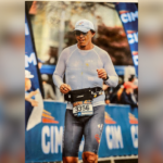 Um homem de terno e gravata borboleta fica em frente a uma parede com o