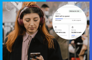 O aplicativo que encontra o dinheiro que você esqueceu que estava gastando Mulher ruiva, usando fones de ouvido, olhando para o telefone em um trem.