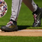 O jogador de beisebol Brandon Pfaadt entra em campo mostrando suas chuteiras pretas e douradas com cadarços rosa.