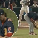 Um arremessador de beisebol se curva no monte após uma lesão, enquanto o receptor e o árbitro se aproximam dele.