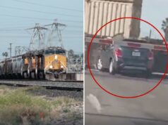 O carro aterrorizante de uma mulher de 18 anos é destruído na ferrovia enquanto ela sofre uma emergência médica Um SUV de cor escura está preso nos trilhos de uma ferrovia enquanto um trem se aproxima, seu pára-choque traseiro batendo na lateral de um vagão de carga.