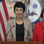 Ilhan Omar fala em entrevista coletiva com Mazie Hirono atrás dela.