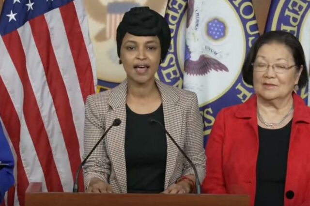 Ilhan Omar fala em entrevista coletiva com Mazie Hirono atrás dela.