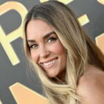 Diane Batoukina usa óculos de sol grandes quadrados marrom escuro da Dior, um vestido longo branco com gola quadrada / cinto de linho, um pulôver de lã com nervuras branco latte no ombro, uma bolsa de couro marrom camelo brilhante com estampa de crocodilo da Ralph Lauren, salto bloco de camurça marrom / botins pontiagudos, durante uma sessão de fotos de moda de estilo de rua, em 28 de abril de 2023 em Paris, França.