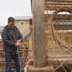 Um homem é retratado em um cais com armadilhas para lagostas em primeiro plano.