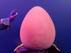 O maior Cadbury Mini Egg do mundo não é nada mini – pesando colossais 120 quilos de chocolate Dois chocolateiros vestindo uniformes roxos pintando o maior Cadbury Mini Egg do mundo.