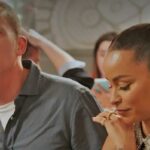 Homem falando enquanto uma mulher olha para baixo com as mãos entrelaçadas.