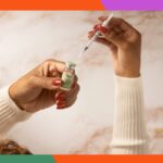 Uma mão segurando duas pílulas ovais verdes com