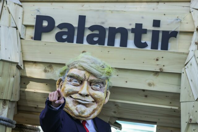 An activist dressed as U.S. President Donald Trump stands in front of a mock Trojan horse