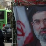 Duas mulheres iranianas passam por uma faixa representando o novo líder supremo do Irã, o aiatolá Mojtaba Khamenei.