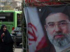 O rosto do líder supremo do Irã, Mojtaba Khamenei, está tão desfigurado que ele precisará de uma cirurgia plástica Duas mulheres iranianas passam por uma faixa representando o novo líder supremo do Irã, o aiatolá Mojtaba Khamenei.