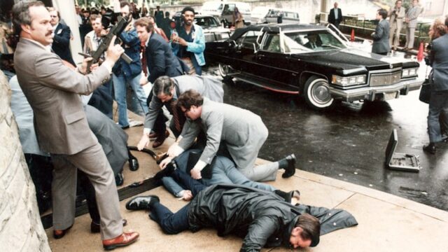 Um assessor de imprensa ferido e um membro do Serviço Secreto estão caídos no local da tentativa de assassinato do presidente Ronald Reagan em 1981.