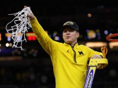 O técnico do Michigan, Dusty May, assinou extensão após ganhar o título nacional O técnico Dusty May, do Michigan Wolverines, segura a rede após derrotar o UConn Huskies.