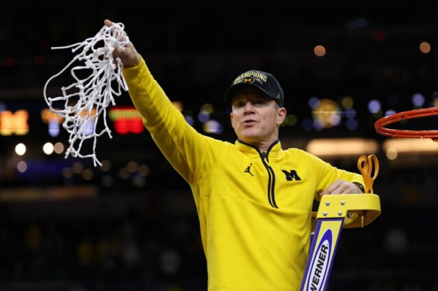 O técnico Dusty May, do Michigan Wolverines, segura a rede após derrotar o UConn Huskies.