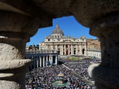 O verdadeiro significado da Páscoa é a base do Cristianismo Ampla vista da Praça de São Pedro repleta de multidão durante a missa de Páscoa, emoldurada por uma abertura arquitetônica.