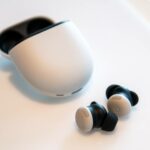 O Google Pixel Buds Pro 2 próximo ao case em uma superfície branca.