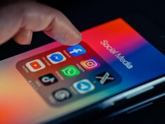 Os consumidores perderam US$ 2,1 bilhões em golpes de mídia social em 2025, relata a FTC finger pointing to Facebook mobile app displayed on a smartphone screen