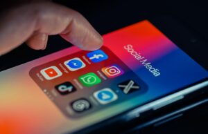 Os consumidores perderam US$ 2,1 bilhões em golpes de mídia social em 2025, relata a FTC finger pointing to Facebook mobile app displayed on a smartphone screen