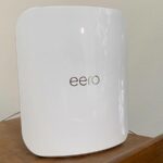 Roteador Netgear com um sinal de alerta no meio sobre um fundo azul e vermelho estampado