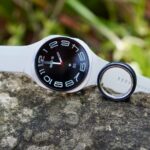 Alguns smartwatches em uma superfície curva com um smartwatch e uma pulseira inteligente ao lado deles.