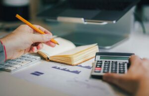 PSA: planos legados ilimitados da AT&T enfrentam aumentos de preços e é uma bagunça Planos ilimitados legados da AT&T enfrentam aumentos de preços e são uma bagunça | Foto mostra um homem com calculadora, notebook e MacBook com gráficos sobre a mesa