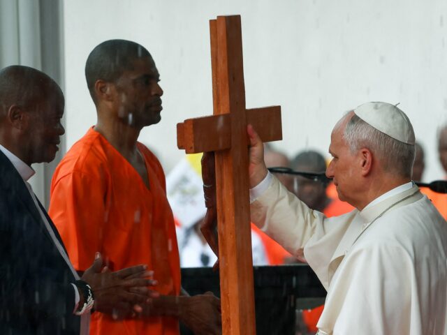 Pessoas usam guarda-chuvas para se proteger da chuva enquanto esperam na rua a passagem do Papa Leão XIV, em Bata, Guiné Equatorial, 22 de abril de 2026. REUTERS/Guglielmo Mangiapane